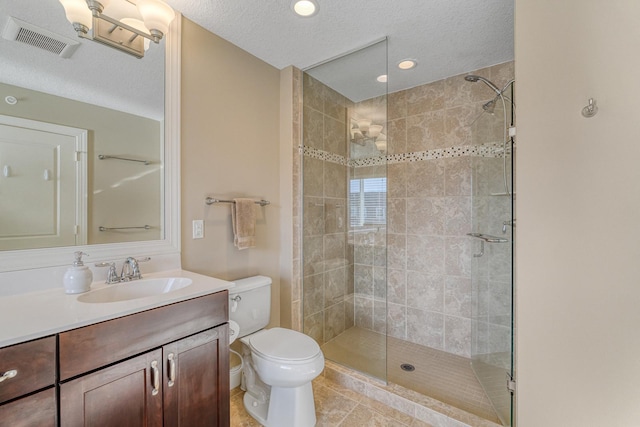 bathroom featuring vanity, tiled shower, a textured ceiling, and toilet