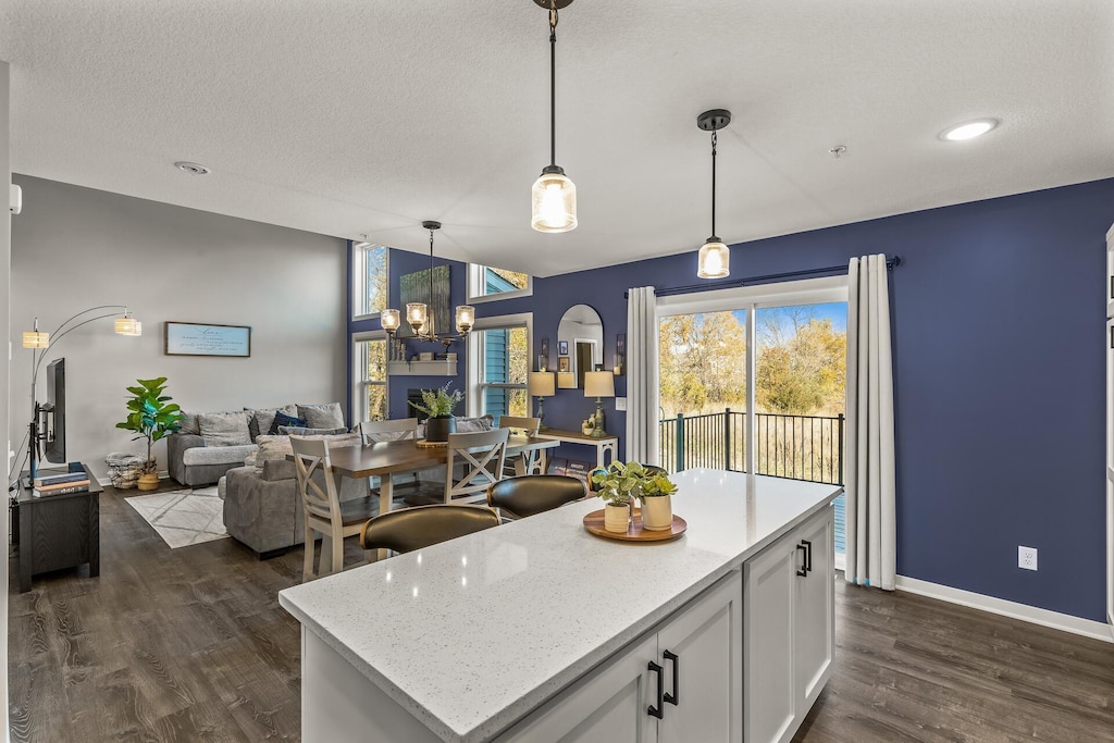 kitchen with a kitchen island, dark hardwood / wood-style floors, decorative light fixtures, white cabinetry, and a chandelier