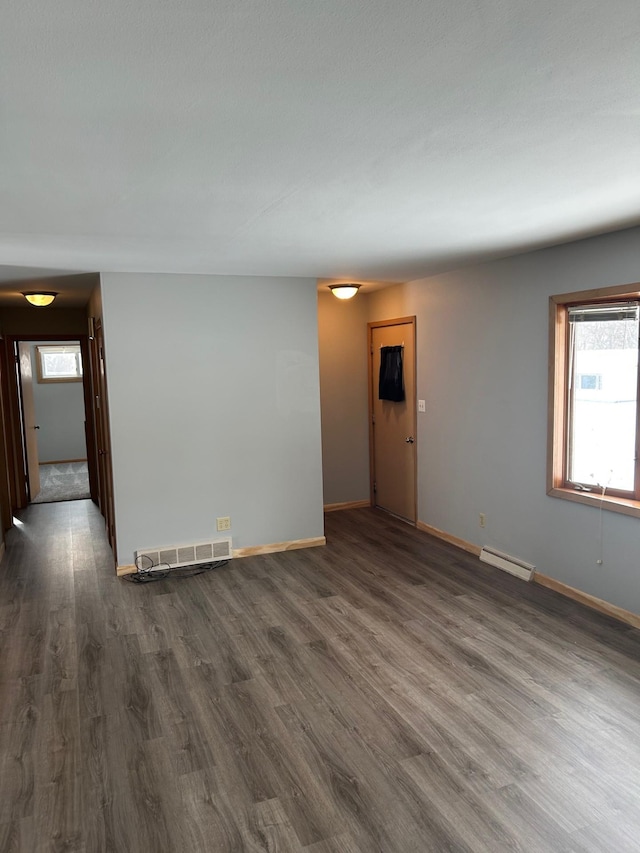 empty room featuring a baseboard heating unit and dark hardwood / wood-style floors