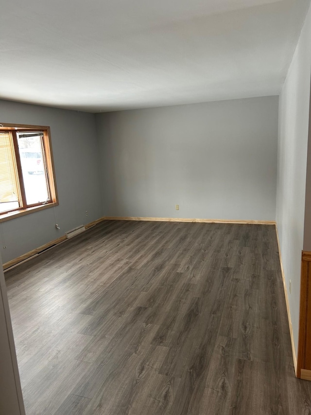 empty room with dark hardwood / wood-style flooring and a baseboard radiator