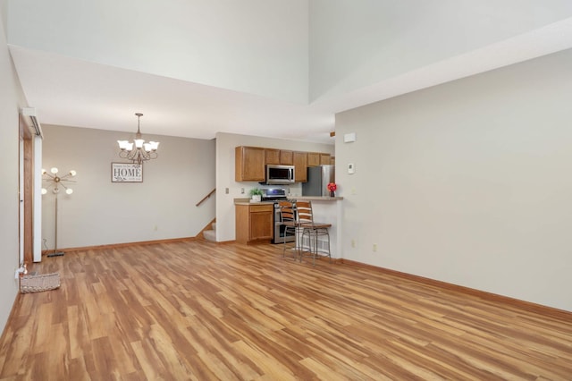 unfurnished living room featuring ceiling fan with notable chandelier and light hardwood / wood-style flooring