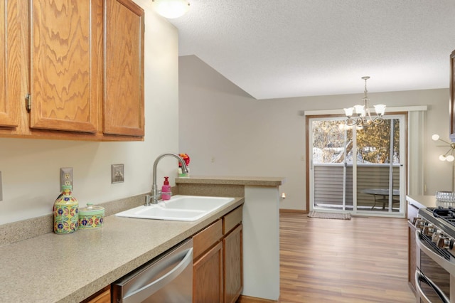 kitchen with sink, stainless steel appliances, decorative light fixtures, a textured ceiling, and a chandelier