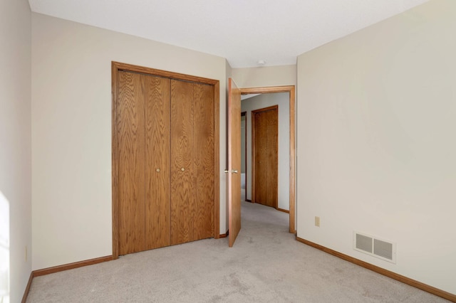 unfurnished bedroom with a closet and light carpet