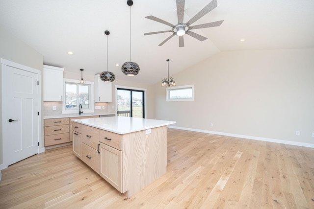 kitchen featuring a kitchen island, light wood-type flooring, vaulted ceiling, and backsplash