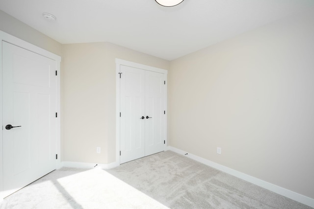 unfurnished bedroom with light colored carpet and a closet