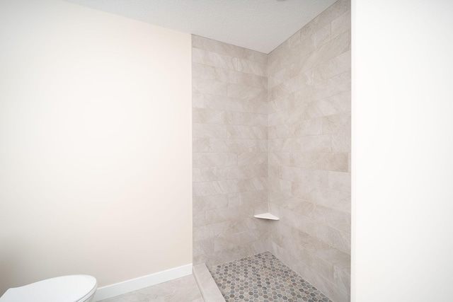 bathroom with tiled shower, tile patterned flooring, and toilet