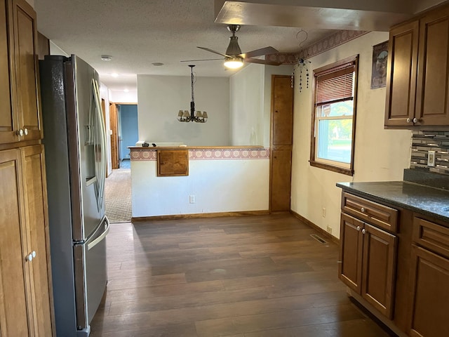 kitchen with stainless steel refrigerator with ice dispenser, decorative light fixtures, dark hardwood / wood-style flooring, a textured ceiling, and ceiling fan with notable chandelier