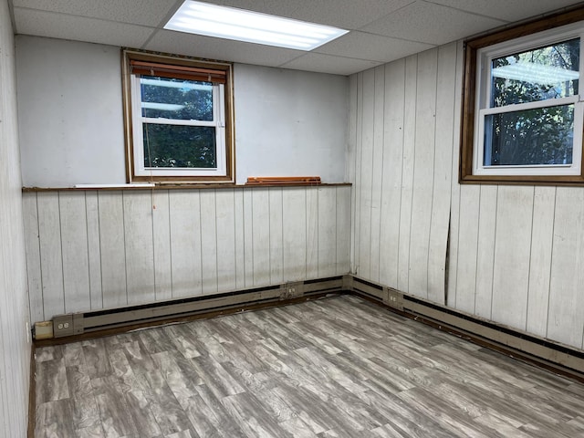 spare room with light hardwood / wood-style floors, a paneled ceiling, and wooden walls