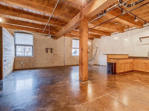 basement featuring ceiling fan, wooden ceiling, and brick wall