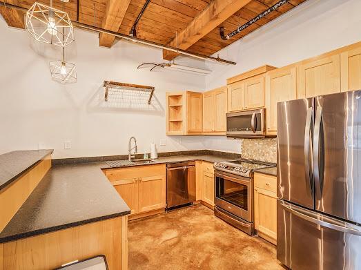 kitchen with appliances with stainless steel finishes, light brown cabinets, tasteful backsplash, hanging light fixtures, and beam ceiling