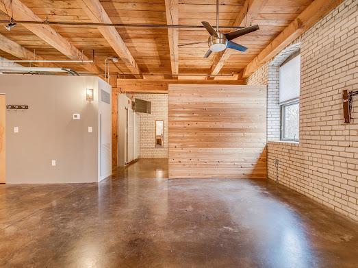 spare room featuring wooden ceiling, ceiling fan, wood walls, concrete flooring, and brick wall