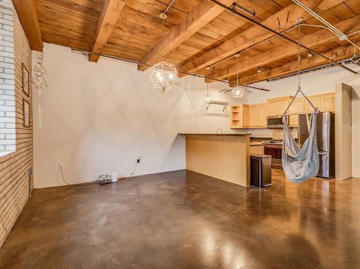 basement with brick wall, stainless steel refrigerator, and wood ceiling