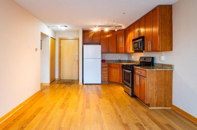 kitchen featuring stone counters, stainless steel appliances, and light wood-type flooring