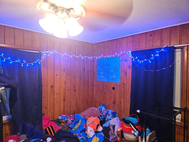 bedroom with wooden walls, a textured ceiling, and ceiling fan