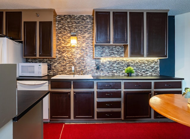 kitchen with decorative backsplash, sink, white appliances, and dark brown cabinetry