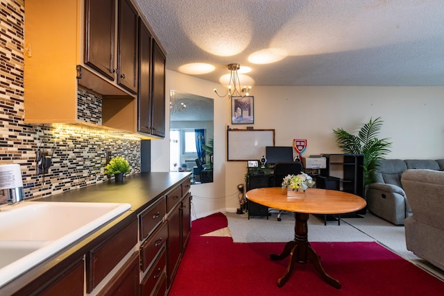 kitchen featuring decorative light fixtures, decorative backsplash, sink, an inviting chandelier, and dark brown cabinets