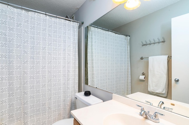 bathroom with a textured ceiling, toilet, and vanity