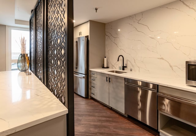 kitchen with light stone counters, sink, appliances with stainless steel finishes, and dark hardwood / wood-style flooring