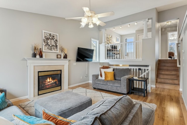 living room with ornate columns, ceiling fan, track lighting, and light hardwood / wood-style floors