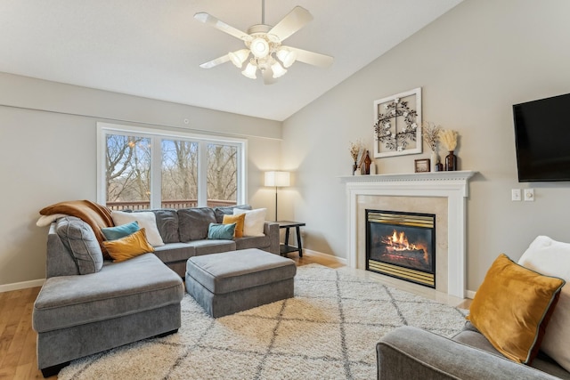 living room with ceiling fan, light hardwood / wood-style floors, and vaulted ceiling