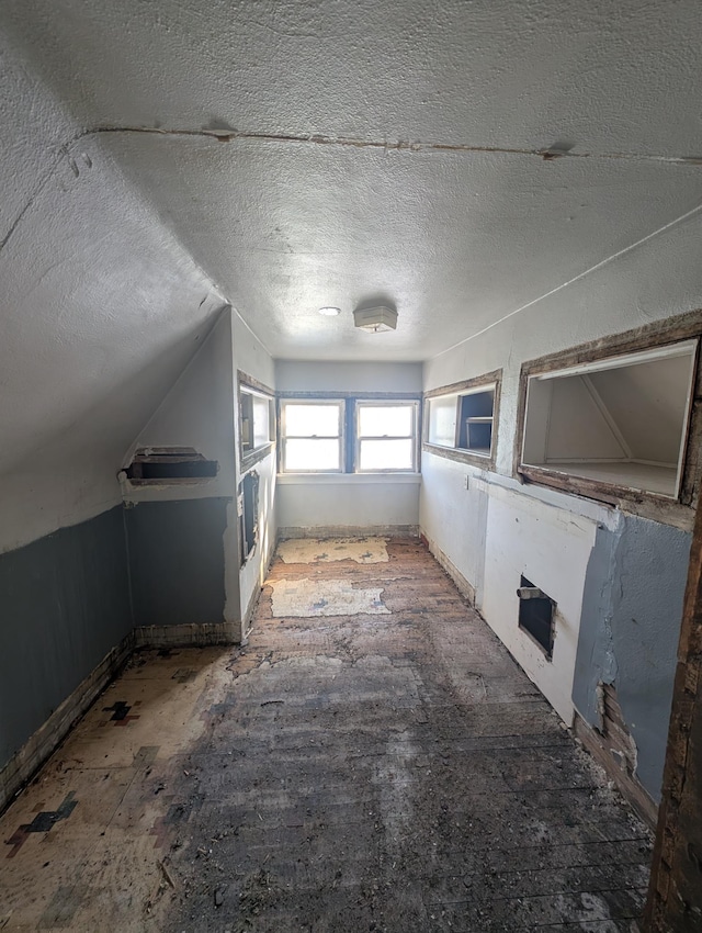 additional living space with lofted ceiling and a textured ceiling