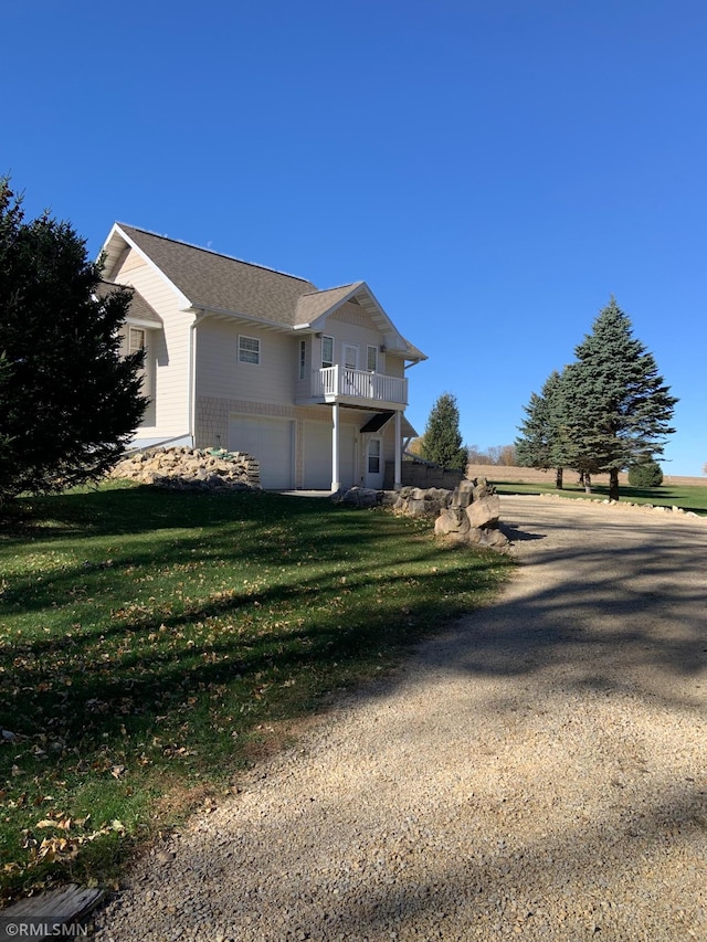 view of side of home with a lawn, a balcony, and a garage