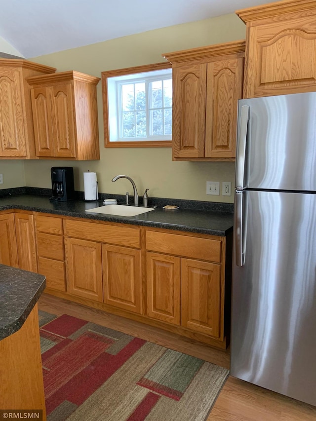 kitchen featuring sink, light wood-type flooring, and stainless steel refrigerator