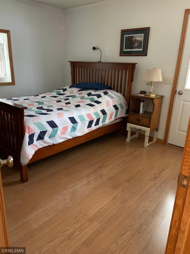 bedroom featuring light wood-type flooring and ornamental molding