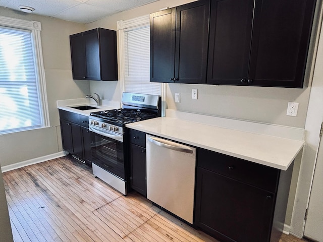 kitchen featuring stainless steel appliances, sink, light hardwood / wood-style floors, and a wealth of natural light