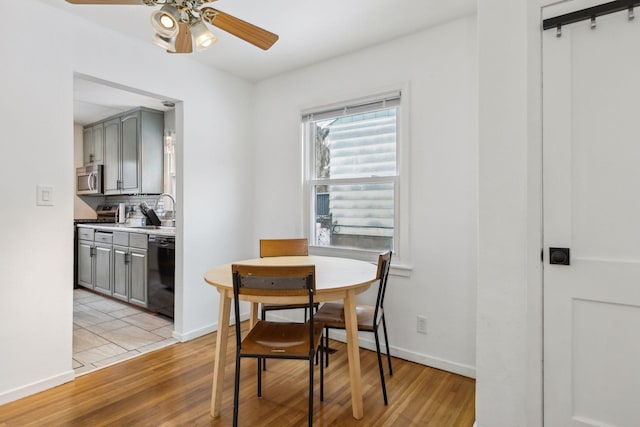 dining space featuring sink, light wood-type flooring, and ceiling fan