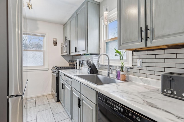 kitchen featuring appliances with stainless steel finishes, decorative backsplash, gray cabinets, and sink