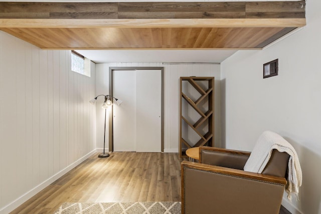 living area featuring light hardwood / wood-style floors, wood ceiling, and wood walls