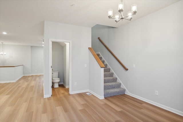 stairs featuring a chandelier and hardwood / wood-style flooring