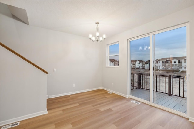 spare room featuring an inviting chandelier and hardwood / wood-style flooring