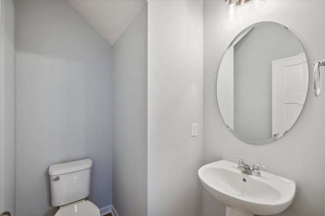 bathroom with sink, toilet, and vaulted ceiling