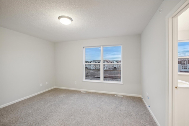 carpeted empty room with a textured ceiling