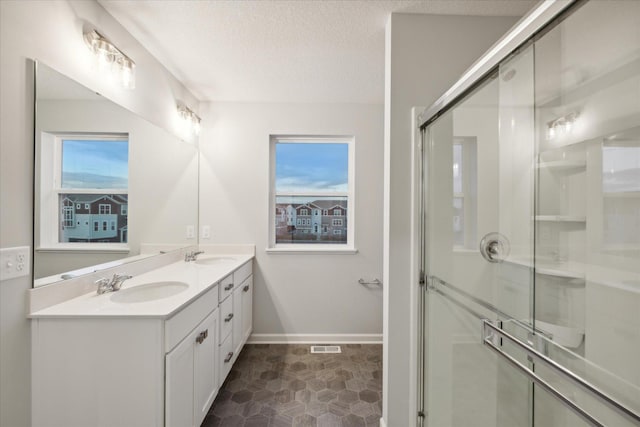 bathroom with a textured ceiling, a shower with shower door, and vanity