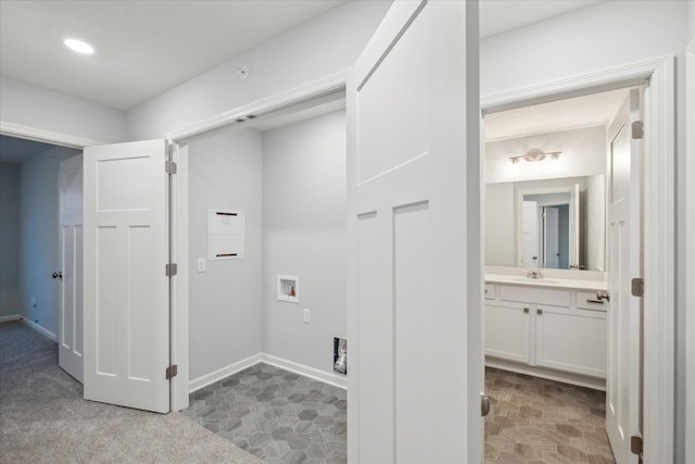 clothes washing area with sink, light colored carpet, and hookup for a washing machine