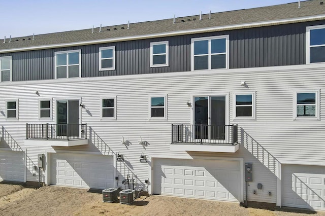 rear view of property with a garage and central air condition unit