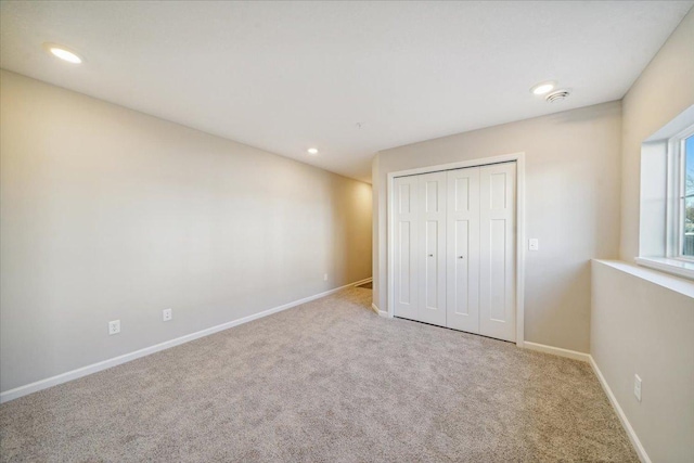 unfurnished bedroom featuring a closet and light colored carpet