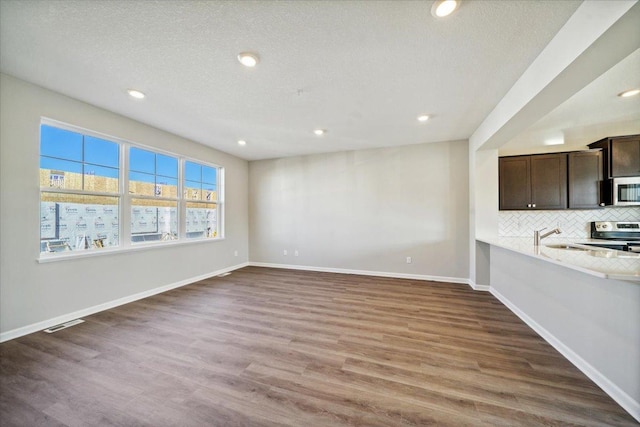 unfurnished living room featuring sink, dark wood-type flooring, and a textured ceiling