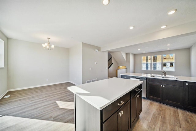 kitchen with sink, light hardwood / wood-style floors, dishwasher, and a kitchen island