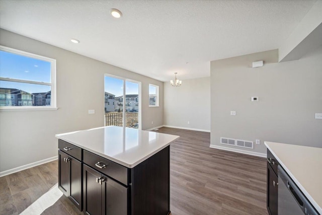 kitchen with a center island, dishwasher, hanging light fixtures, a chandelier, and dark wood-type flooring