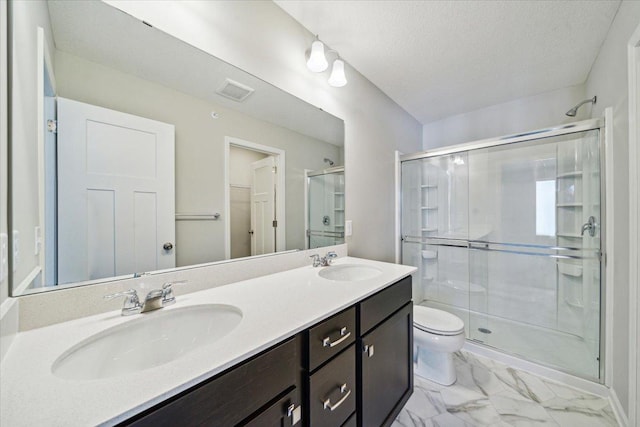 bathroom featuring a textured ceiling, vanity, a shower with shower door, and toilet