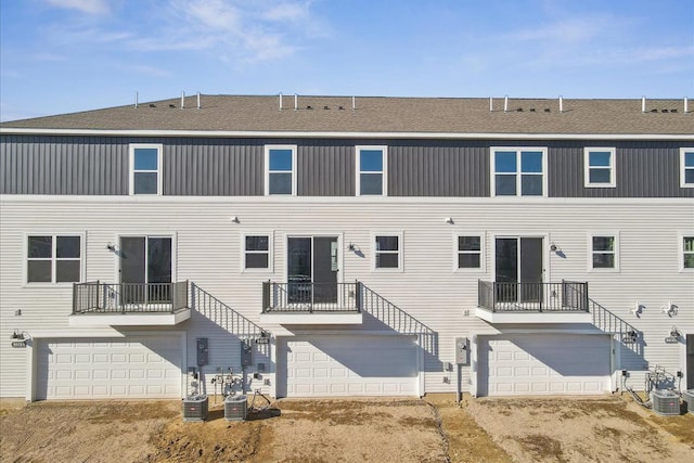 rear view of house featuring a garage and central AC