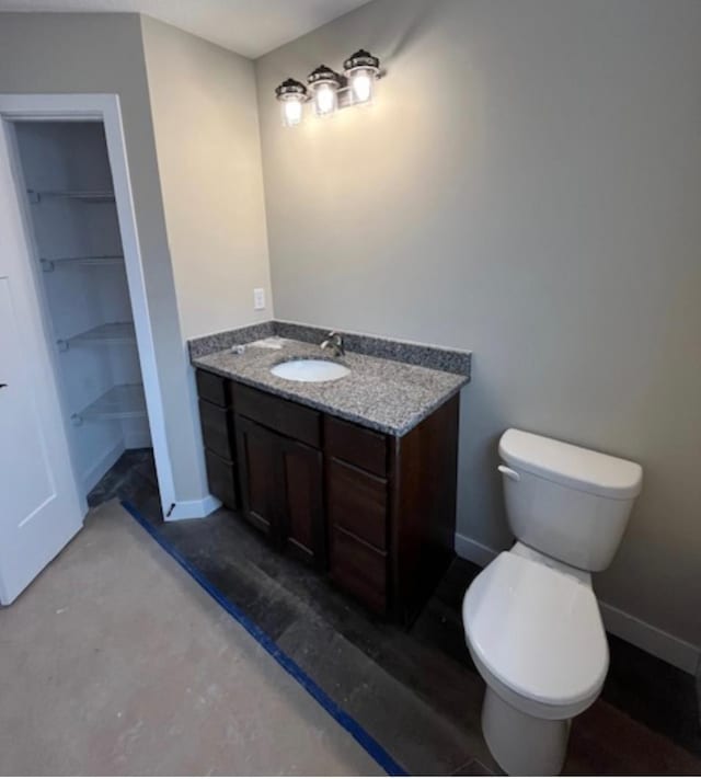 bathroom with concrete flooring, walk in shower, vanity, and toilet