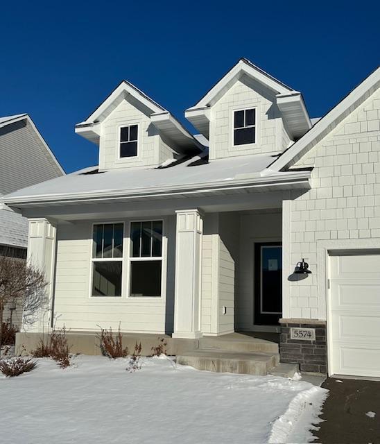 snow covered property entrance featuring a porch and a garage