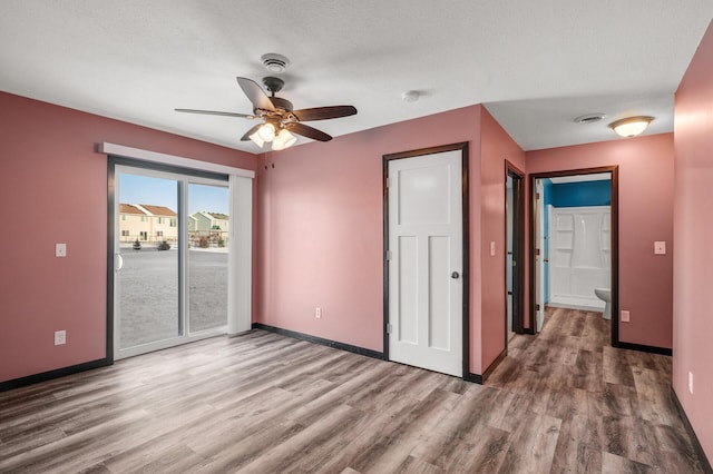 unfurnished bedroom with access to outside, a textured ceiling, connected bathroom, hardwood / wood-style floors, and ceiling fan