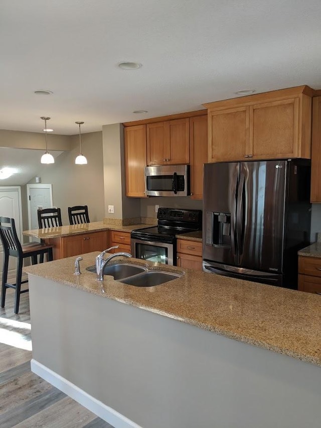 kitchen featuring stainless steel appliances, light stone counters, and kitchen peninsula