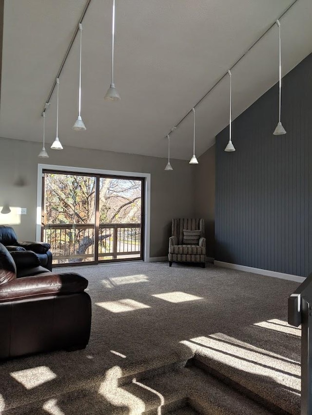 living room with track lighting, carpet flooring, and a towering ceiling